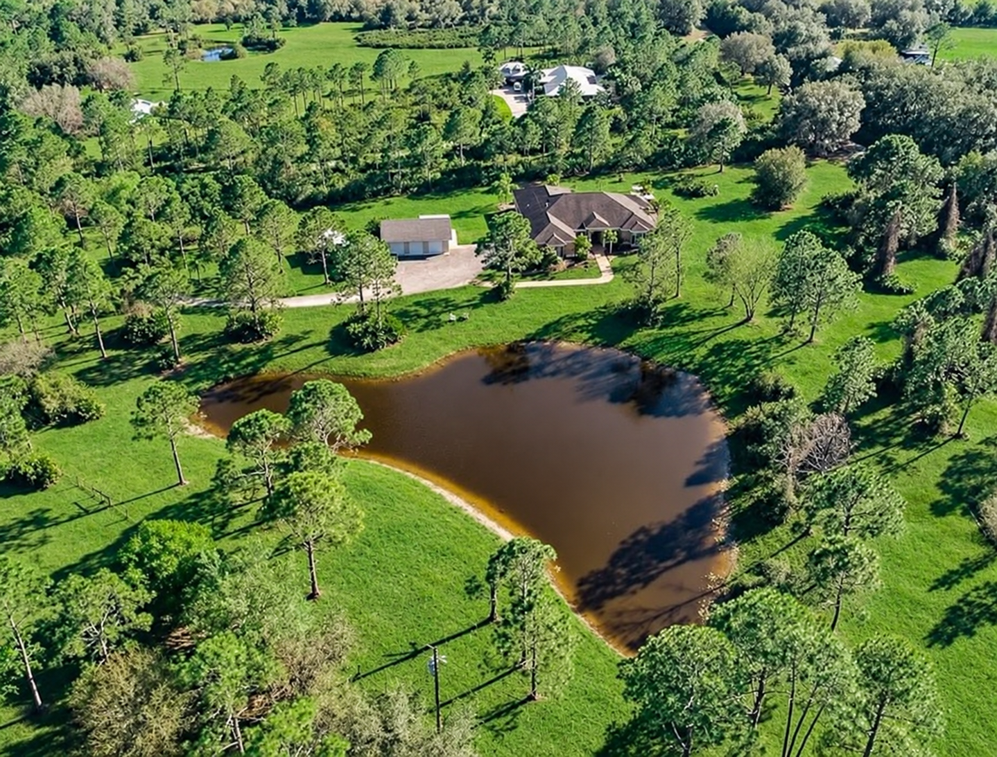 Aerial view of the farm’s pond, green grounds, and surrounding trees